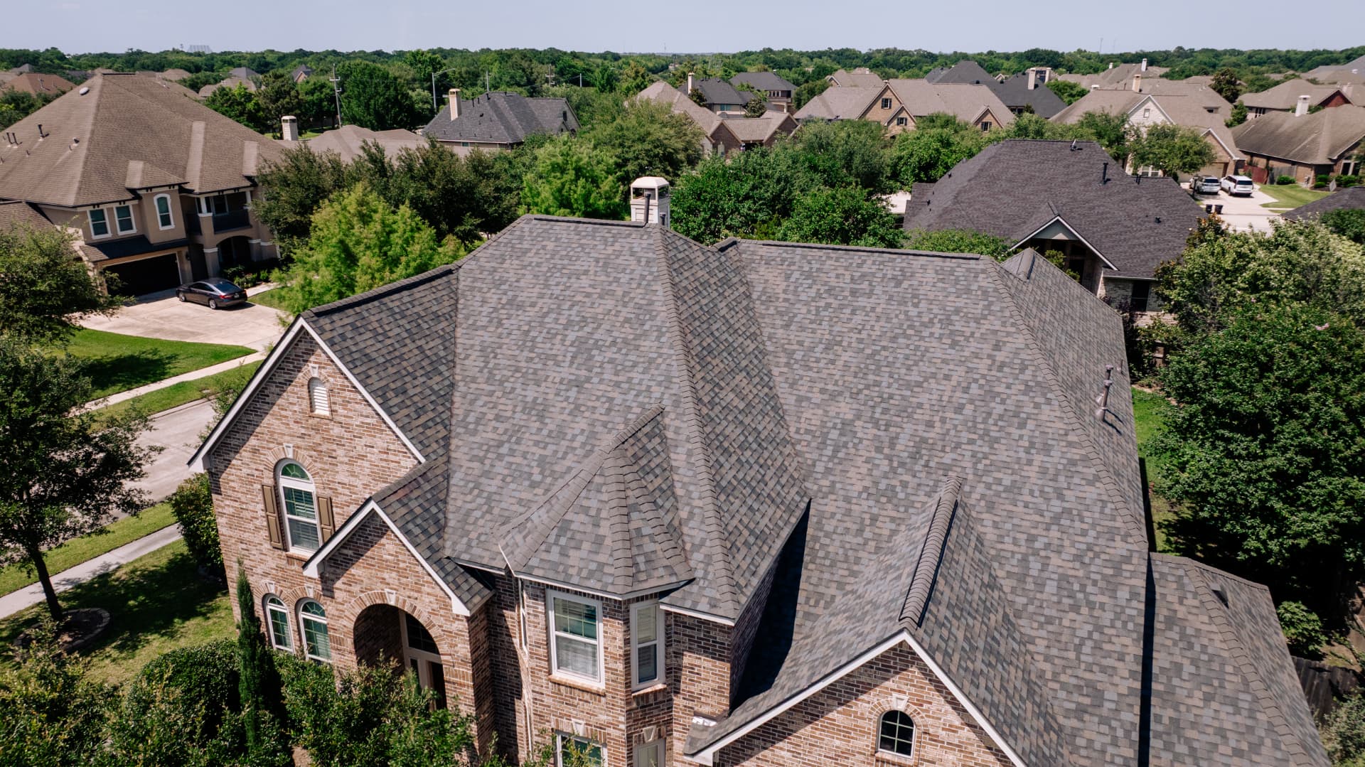 Close aerial view of a completed gray architectural shingle roof in West University Place, TX